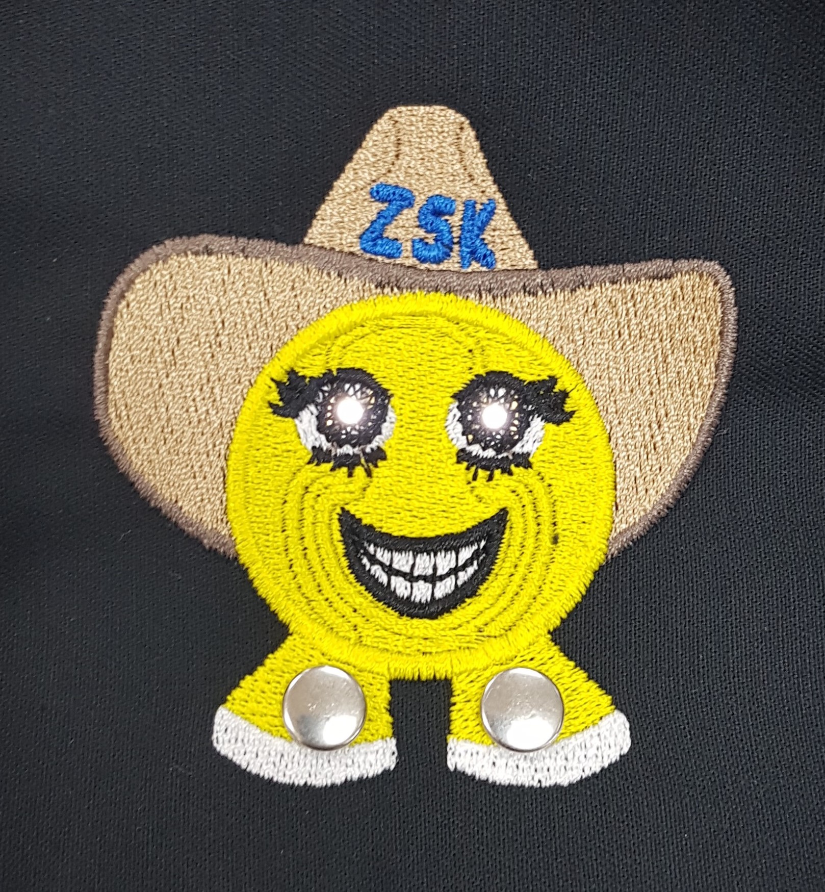 3E Enlightened Smiley - Smart textiles demonstrator, consisting of two ZSK LED Sequins. The conductive traces are covered with non-conductive thread to blend in the design.