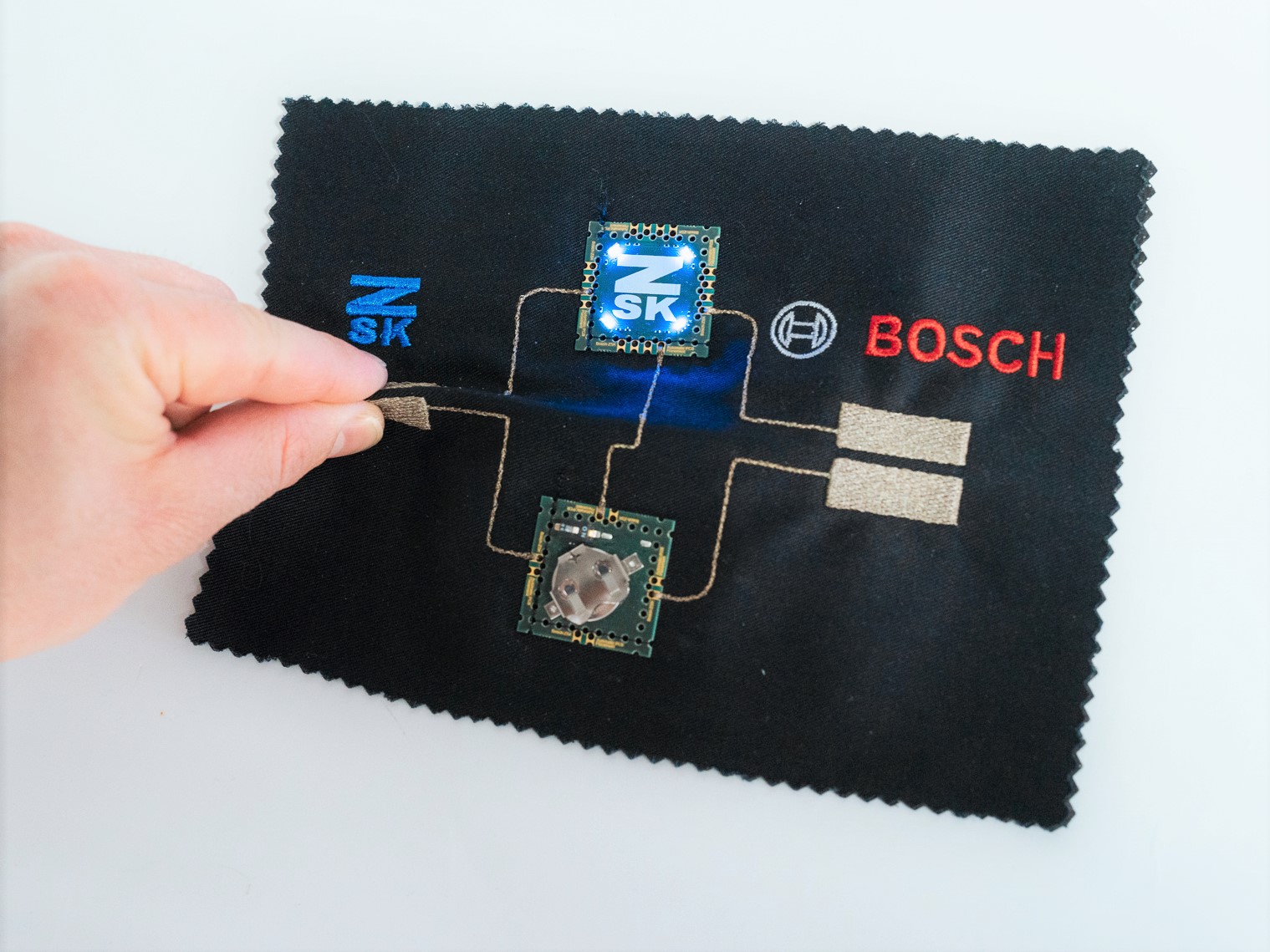 3E "Pinch Me" Demonstrator with two PCBs placed with the ZSK PCB Placement Device as well as two embroidered control elements to turn on the LEDs in blue or red color.